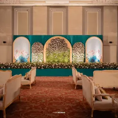A stunning reception stage with a deep teal backdrop and arches filled with flowers. The design is modern yet timeless, providing a sophisticated setting for the couple.