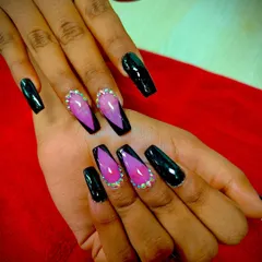A dramatic look combining glossy black coffin nails with accent nails that have a pink-to-black ombre V-French design, outlined with sparkling rhinestones.