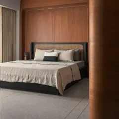 This bedroom showcases a retro 80s influence within a Japandi framework. The custom black bed with a rattan headboard is set against a warm wood-panelled wall, creating a cozy and stylish personal retreat.