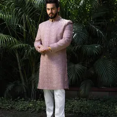 Unleash the power of cultural elegance. This client wears a mauve-pink sherwani with intricate, geometric self-embroidery, showcasing a subtle yet powerful look.
