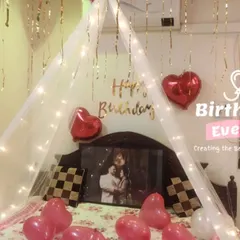 A romantic bed canopy setup. We use sheer white fabric, fairy lights, and heart-shaped balloons to create a dreamy space, complete with a framed photo.