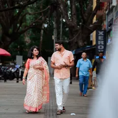 A wider perspective of the couple's stroll, showing the hustle and bustle of the city around them. This documentary-style shot freezes a private moment in a public space, making it feel intimate and real.