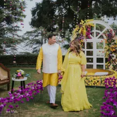 A happy couple at their vibrant Haldi ceremony. The decor combined bright yellow sunflowers with deep purple orchids for a unique and beautiful color palette.