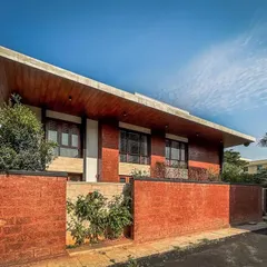 An angular view of the Hennur villa, emphasizing the dramatic sweep of the wooden-clad roof that defines the home's architectural character.