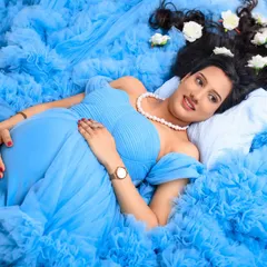 A beautiful close-up of the mom-to-be, capturing her gentle smile and pregnancy glow. This overhead shot highlights her peaceful expression and the stunning texture of the gown.