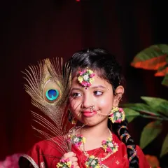 This portrait of a young girl dressed as Radha for Janmashtami is beautifully lit to highlight her festive attire and the delicate peacock feather prop.