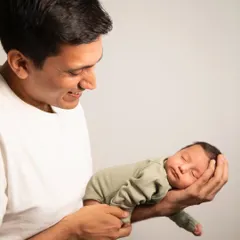 A father's hands, a baby's peaceful sleep. This portrait captures the gentle strength and tenderness of a new dad holding his entire world.