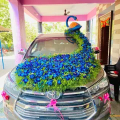 This is my signature peacock themed wedding car decoration on a Toyota Innova. The design features a beautiful peacock figure with a long, flowing tail of blue orchids and greenery covering the bonnet, making it a true showstopper.