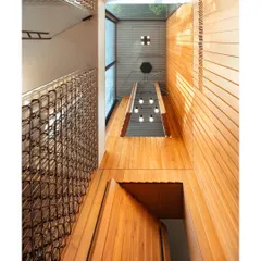 A worm's-eye view of the teak-clad double-height space, emphasizing its verticality and the careful integration of lighting fixtures to create a dramatic yet refined atmosphere.