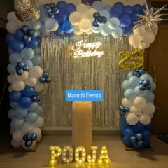 A cool and stylish 23rd birthday for Pooja. This decoration includes a blue and white balloon arch, a silver shimmer curtain, a neon sign, and light-up marquee letters.