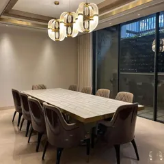 A closer view of the dining set, highlighting the contrast between the textured, patterned tabletop and the smooth, velvety upholstery of the chairs. The warm light from the pendant fixtures enhances the rich materials and inviting atmosphere.