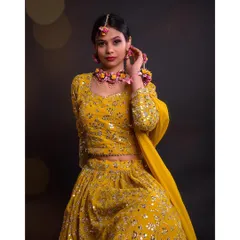 A beautiful close-up of the same festive look. This shot highlights the intricate floral jewelry and the detailed embroidery on the yellow lehenga, perfect for a haldi ceremony or spring wedding.