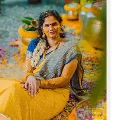The bride, covered in turmeric paste, smiles for the camera in a moment of calm during her vibrant Haldi ceremony.