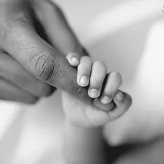 A newborn's hand instinctively curling around a parent's finger is a powerful symbol of trust and connection, made even more impactful in classic black and white.