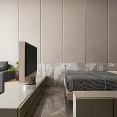 This guest room transforms into a family entertainment space thanks to a custom-designed rotating TV console. The unit acts as a room divider, allowing the screen to swivel 180 degrees to serve either the cozy seating area or the bed, maximizing functionality in a compact room.