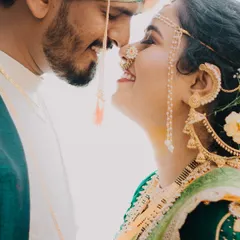 An intimate nose-to-nose moment that highlights the bride's stunning traditional jewelry and the groom's loving gaze. This close-up from a Maharashtrian couple shoot captures the delicate details and the deep affection between them.