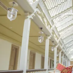 An artistic shot focusing on the groom's traditional wedding shoes (mojari), placed on a railing with a beautifully blurred architectural background.