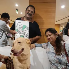 A happy couple with their beautiful dog, posing with their family caricature at a OnePlus event for pet lovers.