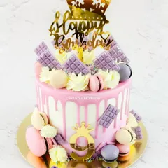 A pretty pink drip cake perfect for a royal celebration. This Ferrero Rocher-flavoured cake is adorned with macarons, mini chocolate bars, and gold crown toppers for a fun and regal look.