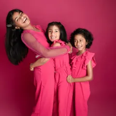 The energy of these three sisters is just infectious. Using a vibrant pink backdrop makes their joyful personalities pop in this fun sibling photoshoot.