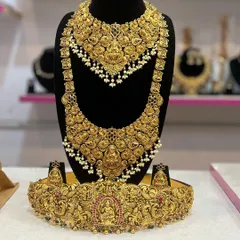 A complete view of one of our grandest temple jewellery sets. This collection includes a short necklace, a matching long haram, an intricately carved vaddanam (waist belt), and earrings, all featuring Lakshmi motifs with a rich, matt gold finish.