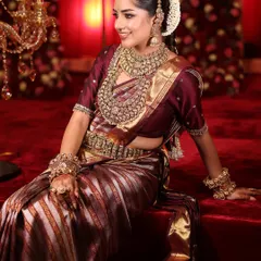 A happy, smiling South Indian bride, her joy lighting up the room as much as her golden jewellery.