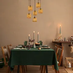 A cluster of woven amber pendants hangs over a festive dining table, creating a warm and intimate atmosphere. The lighting is perfect for making holiday celebrations shine brighter with elegance.