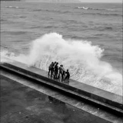 A group of friends braving the powerful waves at Marine Drive. This black and white shot emphasizes the raw power of the sea during high tide.