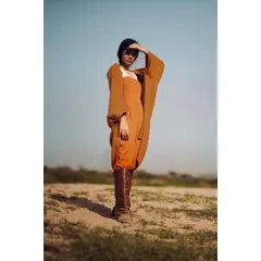 An on-location fashion shoot in a stark, open landscape. The model's pose and the earthy tones of the outfit create a powerful, editorial image that tells a story of strength and exploration.