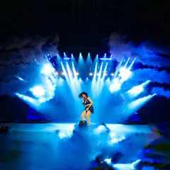 A stage drenched in blue light and smoke. We use professional lighting and atmospheric effects like pyros and smoke to build drama and match the energy of every song.