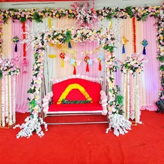 This is a traditional baby shower decoration with a decorated swing as the centerpiece. The backdrop is made of pink and white drapes with floral borders and hanging decorations.