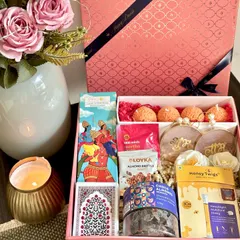 A beautiful Moroccan-print pink box sets the stage for this delightful Diwali hamper. Inside, you'll find Phool incense sticks, playing cards, almond brittle, ladoo candles, and other festive goodies, perfect for sharing with loved ones.
