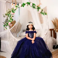 Every little girl deserves to feel like a princess. For this kids' photoshoot, she’s wearing a sparkling navy blue ball gown and sitting on our boho-themed hanging chair, creating a perfect fairytale moment.