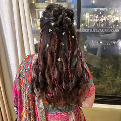 For this vibrant Mehendi look, I styled a half-updo with loose waves and incorporated pink thread braids and small gold clips for a playful and colorful touch.