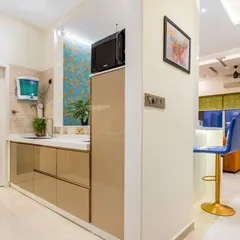 A view from the kitchen into the living area of the same Mumbai home, showing the open layout and the stylish breakfast bar with blue stools.