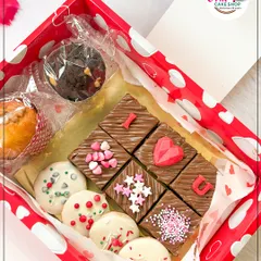 A Valentine's Day gift box filled with love. It includes "I ❤️ U" brownie bites, white chocolate-dipped cookies, and a chocolate cupcake.