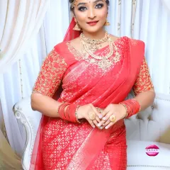 A beautiful standing portrait of a South Indian bride. Her red saree, detailed temple jewellery, and the elegant hair bun with flowers create a timeless and classic wedding look.