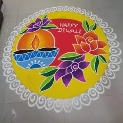 This circular rangoli has a bright yellow base to make the colors pop. It features a large central diya, floral patterns, and a "Happy Diwali" greeting, all enclosed in a delicate white lace-like border.