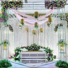 A beautiful Valima stage with a rustic-chic aesthetic. We used a white truss structure, draped pink fabric, and hung wicker baskets with flowing flowers to create a soft and romantic ambiance.