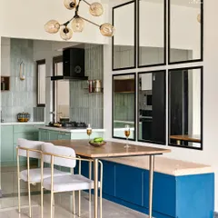 This dining area seamlessly connects to the kitchen, perfect for a family that loves open living. The design uses a bold blue bench for storage and seating, while a wall of mirrors makes the space feel larger and brighter.