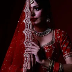 A coy pose with the bride partially hiding her face with her dupatta. This shot plays with shadow and mystery, focusing on her eyes and the rich texture of her veil.