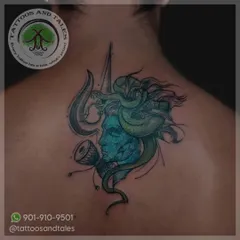 This abstract Lord Shiva tattoo on the upper back uses a striking blue-green color palette to highlight the deity's face, Trishul, and Damaru. It's a modern take on a classic spiritual design.