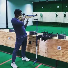 A student practices with an air rifle, using a stand for support. This helps beginners focus purely on aiming and trigger discipline.