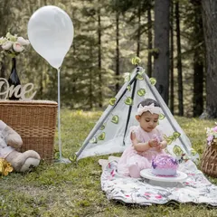 The complete first birthday picnic setup in a forest clearing. This wide shot shows all the elements I bring together, including a teepee tent, a giant teddy bear, and themed decorations for the cake smash.