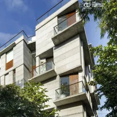 The facade of the Boat Club Apartments features angled, cantilevered balconies that create a dynamic rhythm while providing essential shade and private outdoor spaces for each residence.