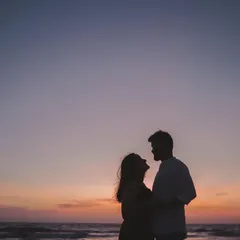 A classic silhouette of a couple against the vibrant colors of a sunset sky over the ocean. These are the timeless, romantic shots that become cherished memories.