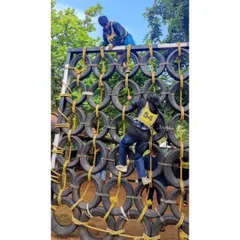 A duplicate of participants tackling a tire wall obstacle. Our leadership camps involve challenging physical activities that build confidence.
