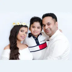 A happy family portrait with their young son. The mother's floral crown adds a soft, celebratory touch to this bright and cheerful at-home studio photo.