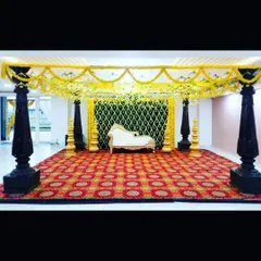 A classic mantap I constructed for a traditional ceremony. The design features four ornate black pillars, a canopy of bright yellow marigold garlands, and a decorative backdrop, all set upon a richly patterned carpet to create a grand and sacred space.