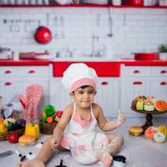 A cheeky grin from our little chef. The red and white kitchen backdrop makes these portraits pop.
